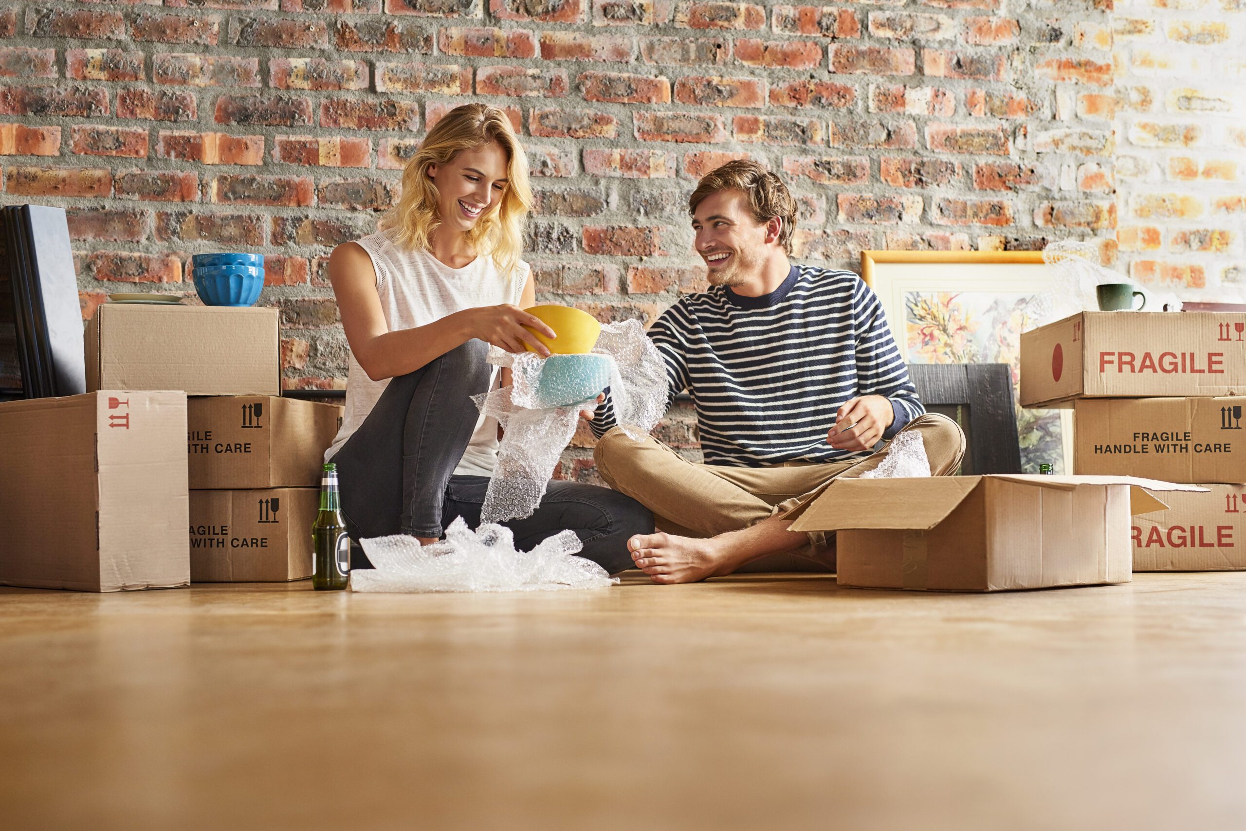 Happy couple unpacking cardboard boxes at new home