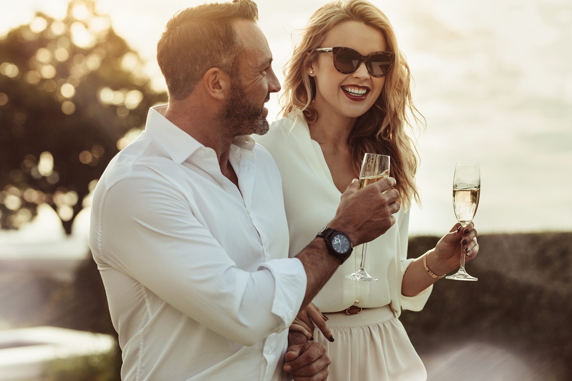 Smiling man and woman enjoying a glass of wine outdoors